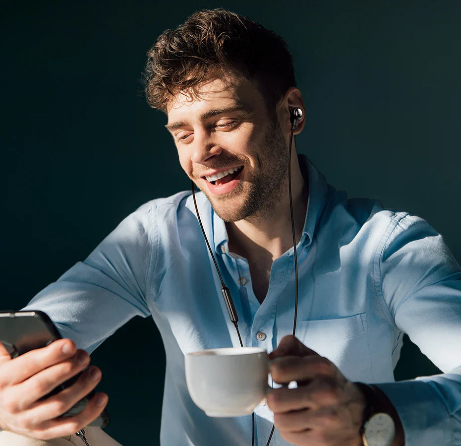 Man with headphones, phone, and coffee.