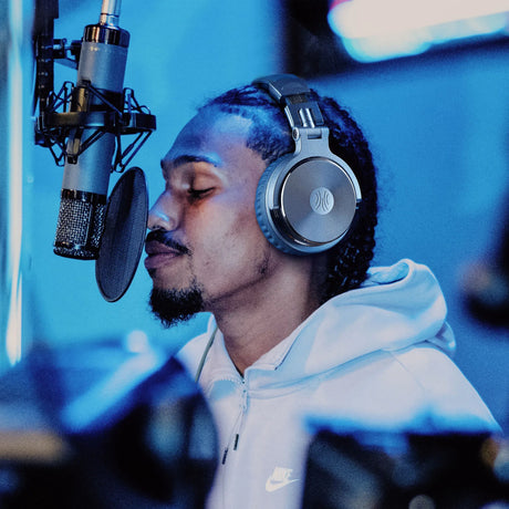 Man singing into microphone with headphones.