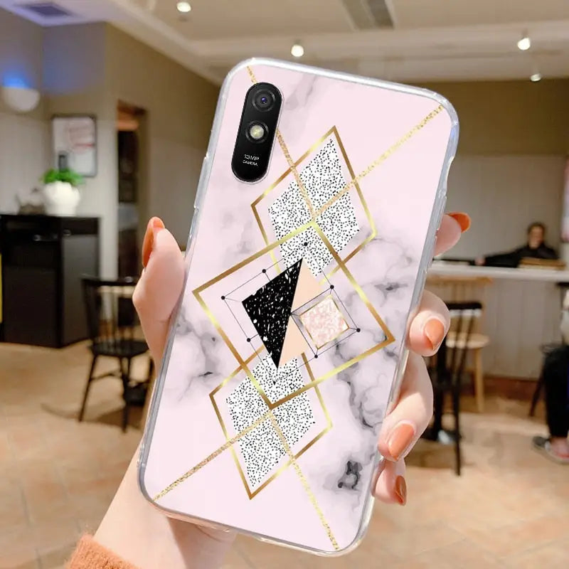 a woman holding up a phone case with a marble pattern