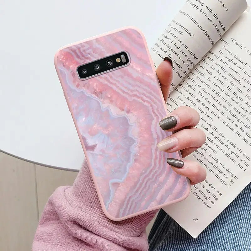 a woman holding a pink marble phone case