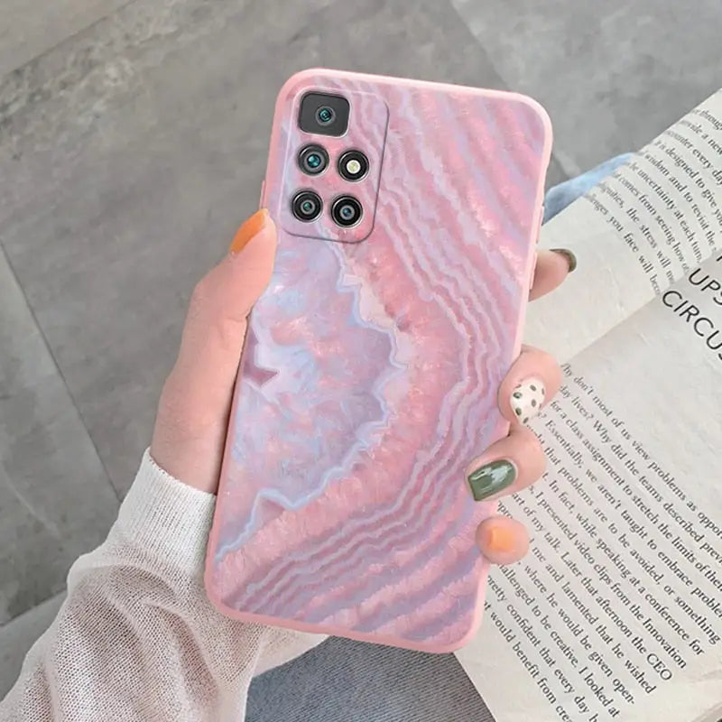 a woman holding a pink marble phone case