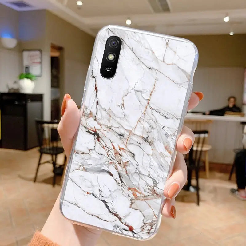 a woman holding a white marble phone case