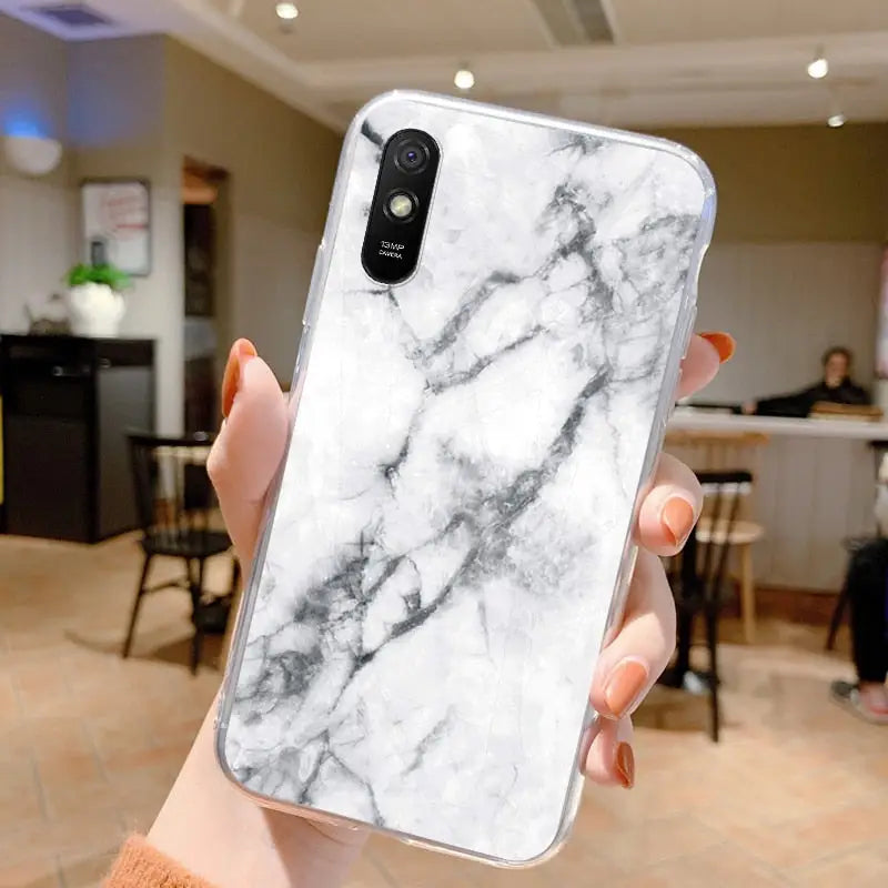 a woman holding a white marble phone case