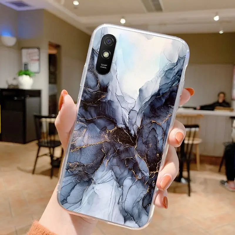 a woman holding up a phone case with a marble pattern
