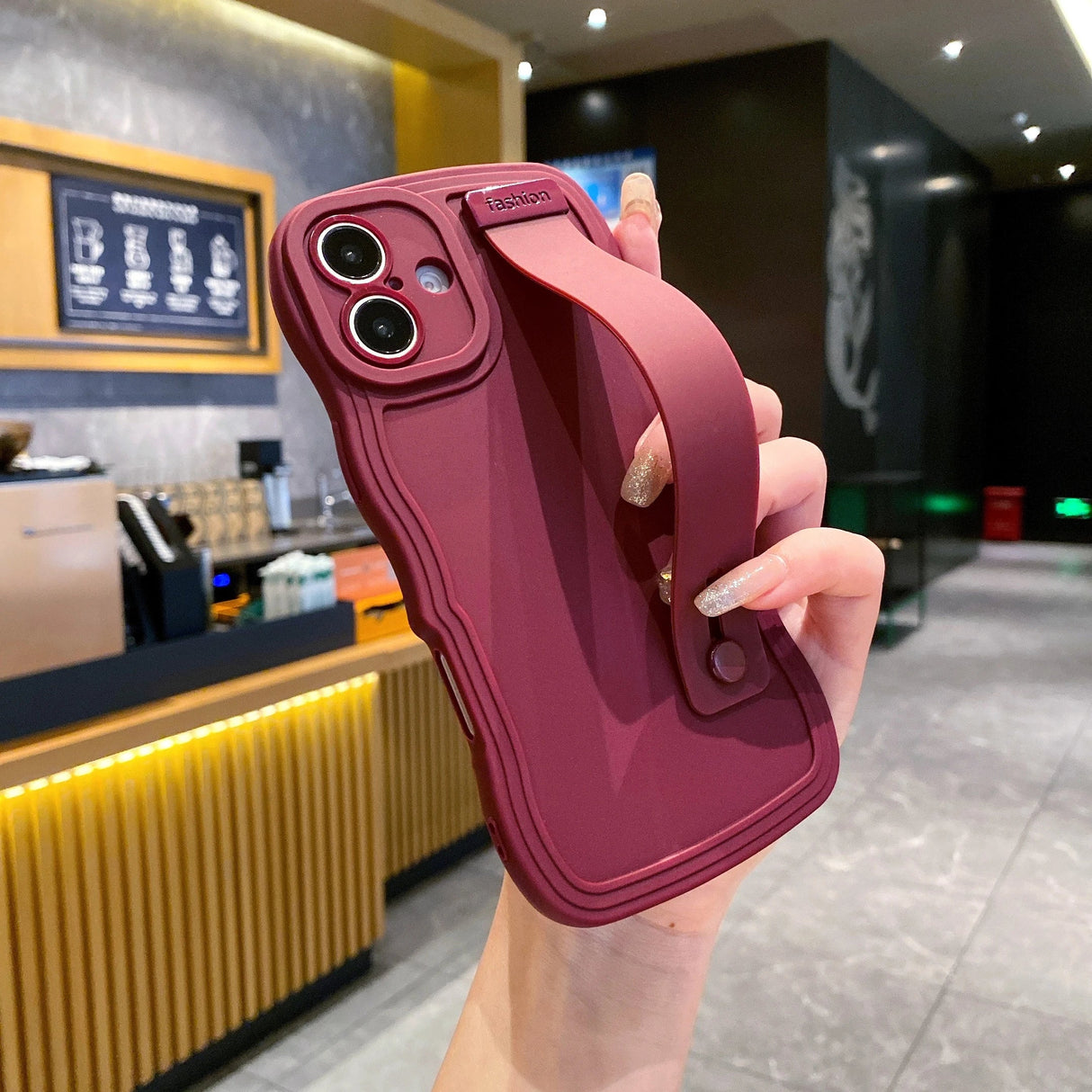 Maroon phone case with hand strap.