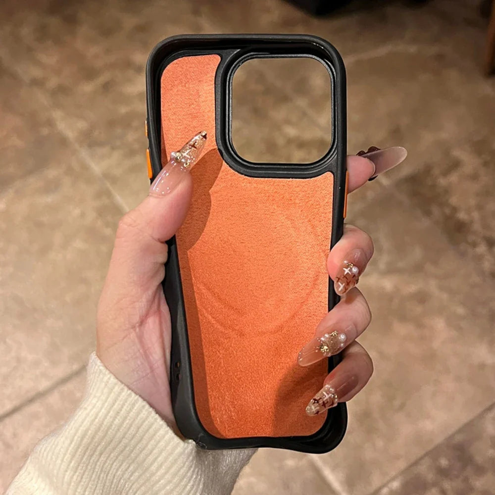 An orange and black iPhone case with a clear camera cutout, held by hands with ornate, long fingernails.