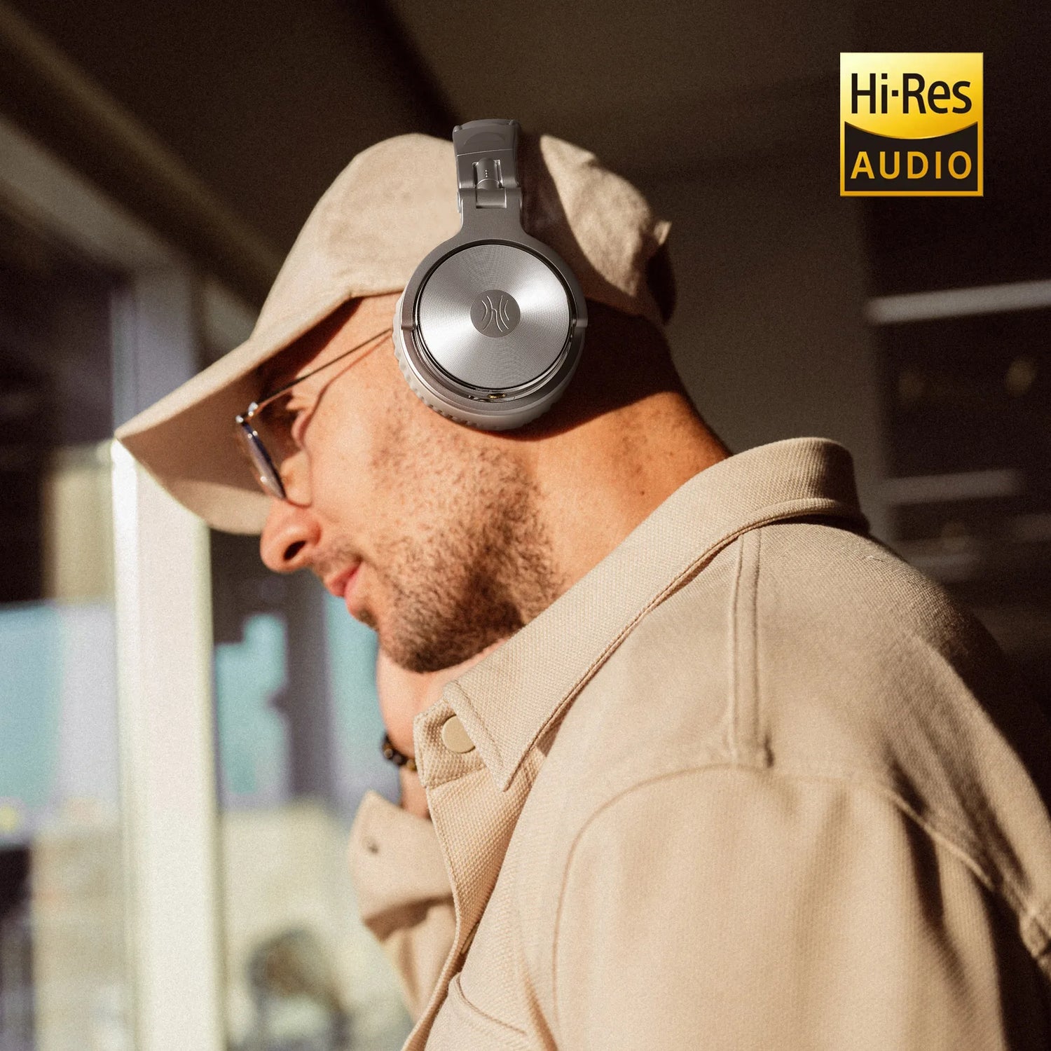 Over-ear headphones worn by a person in a beige outfit and hat.