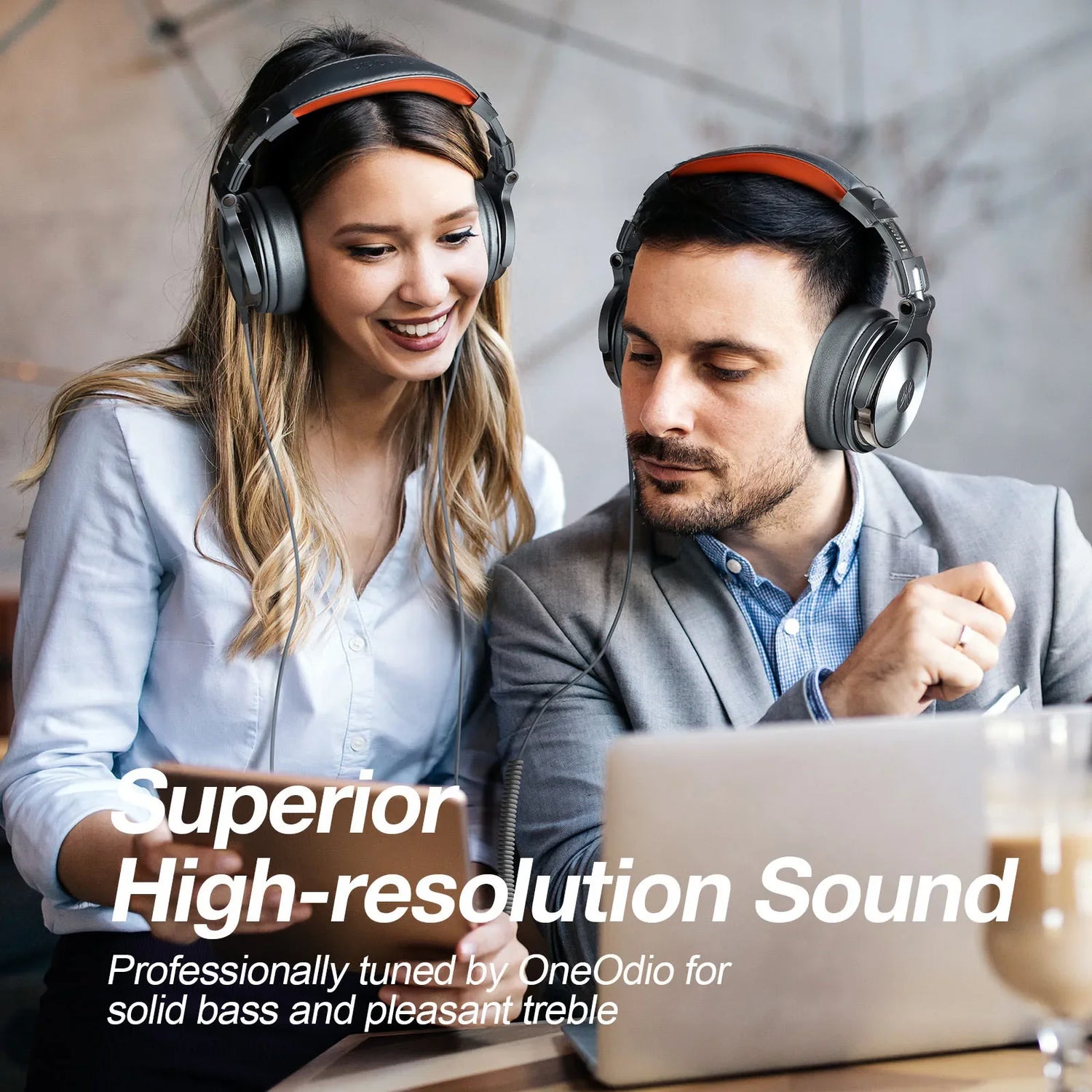 Pair of over-ear headphones worn by two people looking at a laptop.