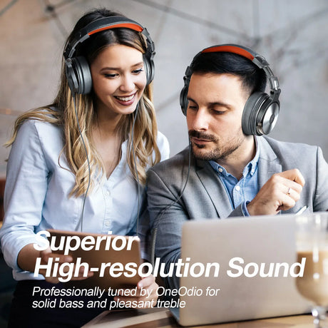 Pair of over-ear headphones worn by two people looking at a laptop.