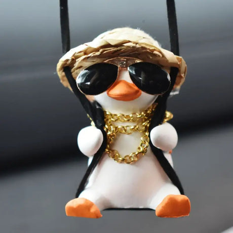 a penguin wearing sunglasses and a hat hanging from a car