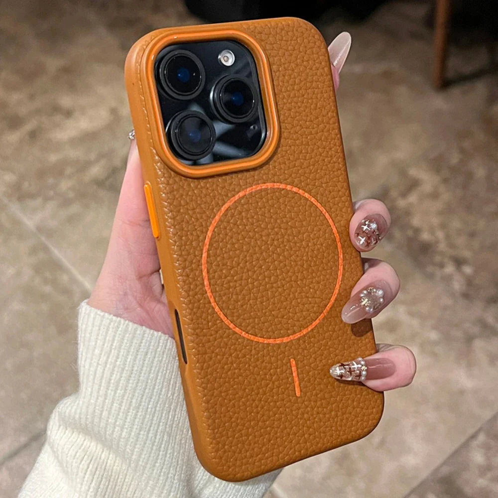 A person holding a brown leather iPhone case with an orange camera ring and MagSafe symbol.