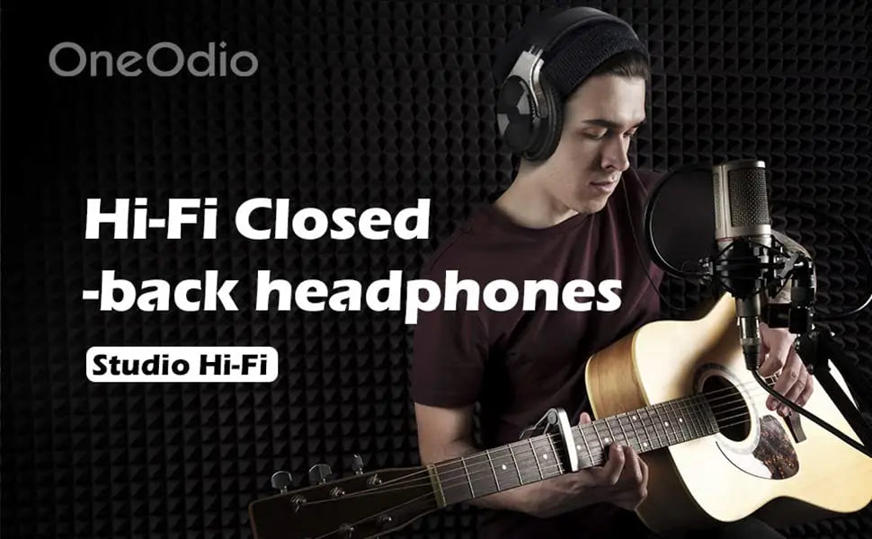Person wearing headphones playing an acoustic guitar in front of a microphone.