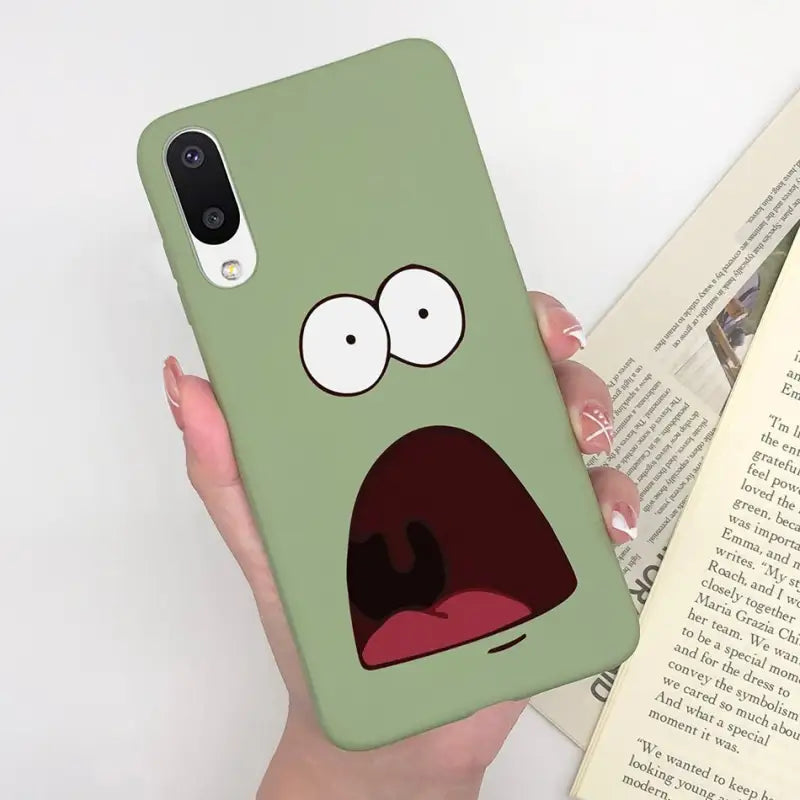 a person holding a book with a green phone case