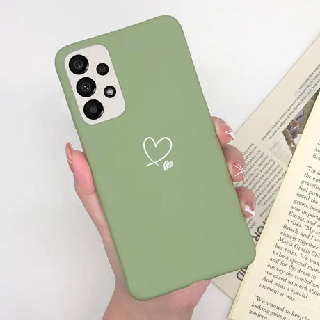 a woman holding a green phone case with a heart on it