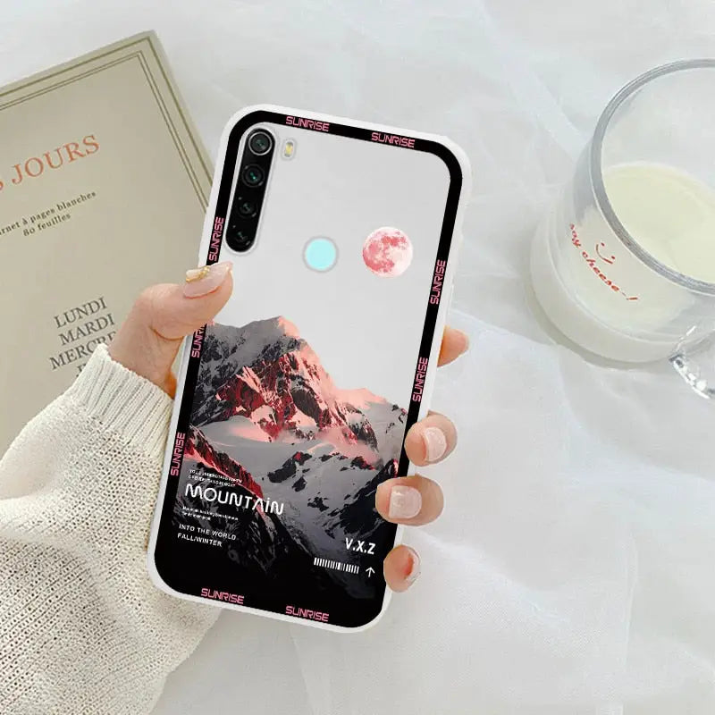 a woman holding a phone case with a pink sunset on it