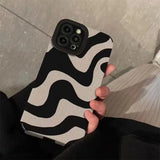 a person holding a phone case with a black and white pattern