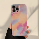 a person holding a phone case with a pink and blue cloud pattern