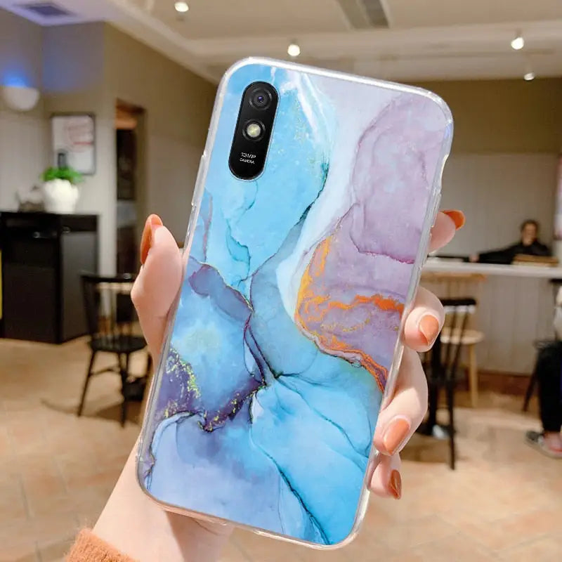 a woman holding up a phone case with a painting on it