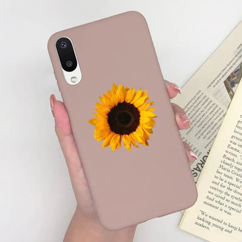 a woman holding a phone case with a sunflower on it