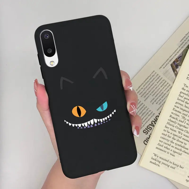 a person holding a phone case with a black cat face