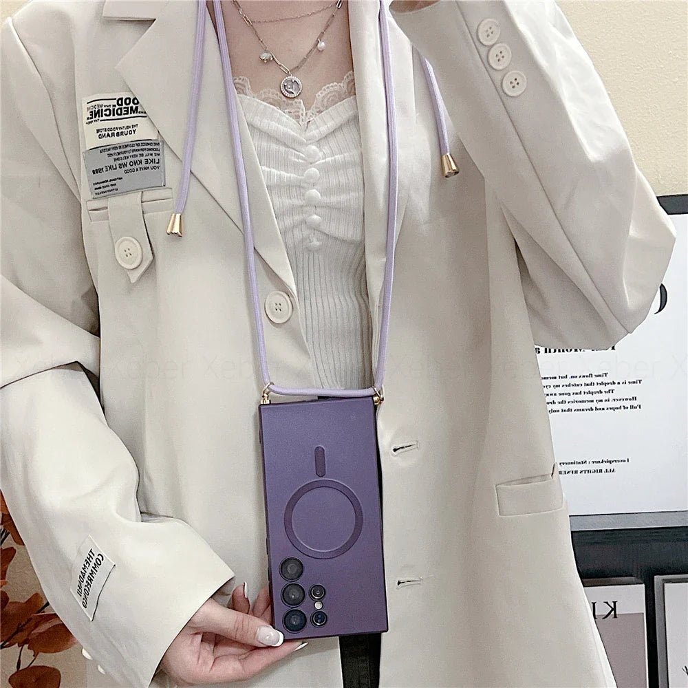 A person wearing a light-colored blazer, a white top, and a layered necklace, holding a purple smartphone case with a built-in lanyard.