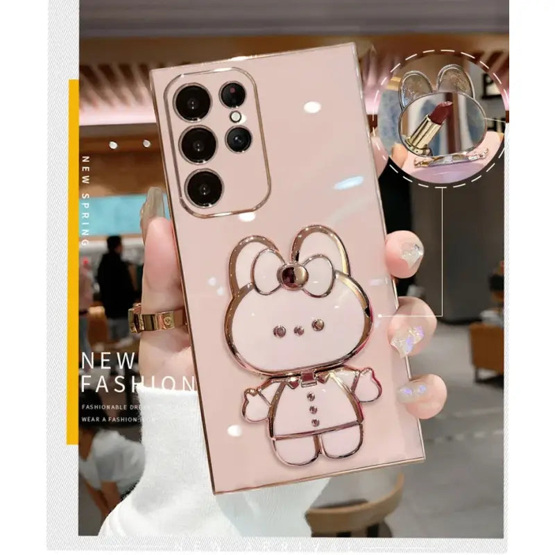 A person holding a pink phone case with a hello bear