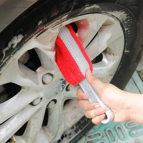 a person using a sponge to clean the rim of a car
