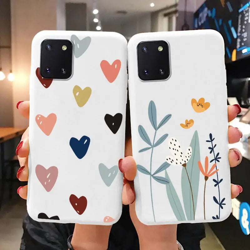 two women holding up their phone cases with hearts and flowers