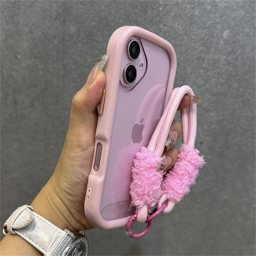 Pink iPhone in a protective case with a fluffy strap.