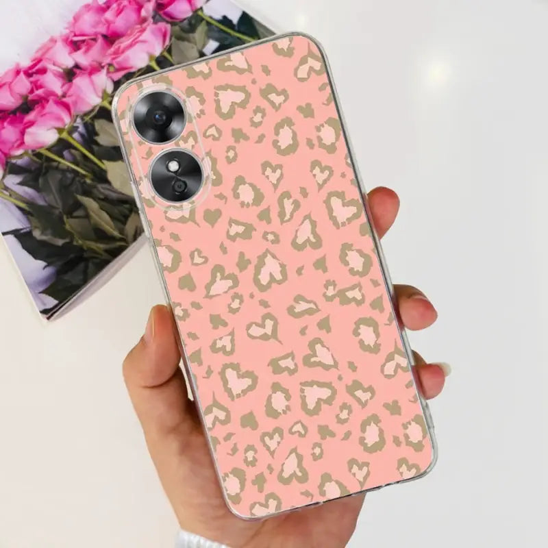 a woman holding a pink and gold leopard print iphone case