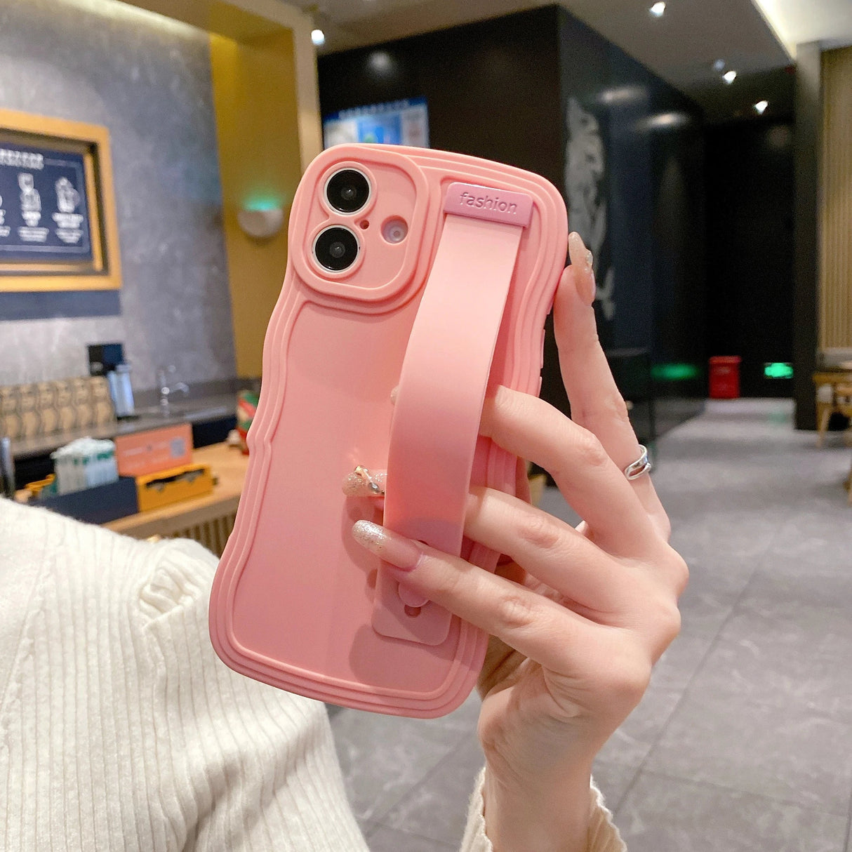 Pink phone case with hand strap.