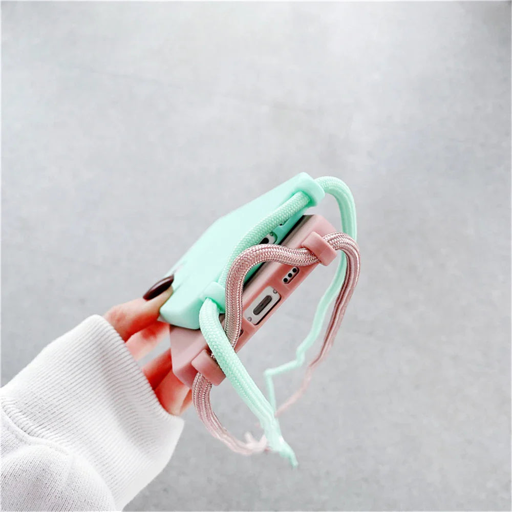 A pink smartphone in a mint green and pink strapped phone case.