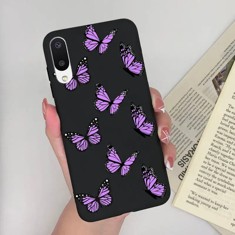 a woman holding a phone case with purple butterflies on it