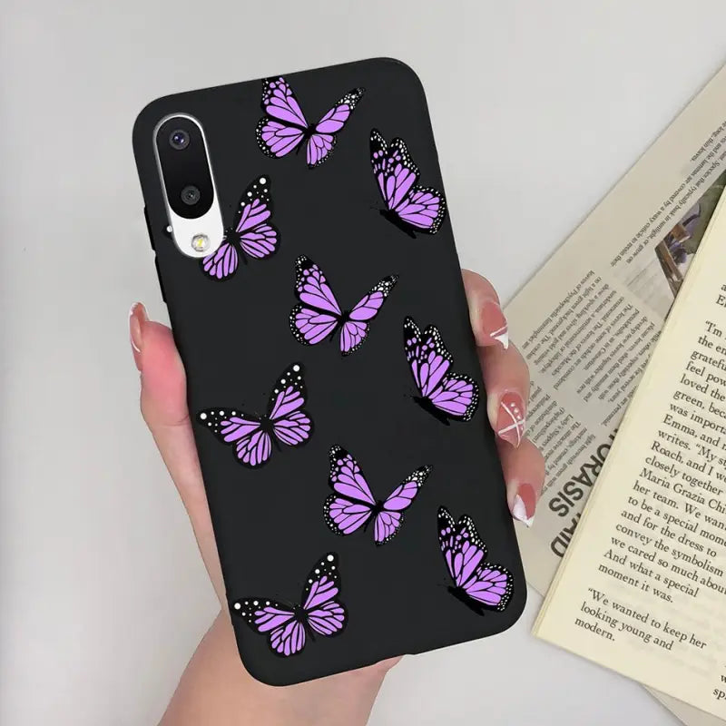 a woman holding a phone case with purple butterflies on it