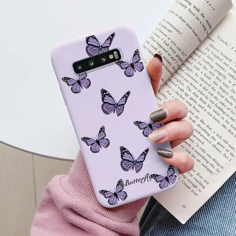 a woman holding a purple phone case with butterflies on it