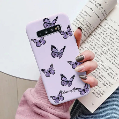 a woman holding a purple phone case with butterflies on it
