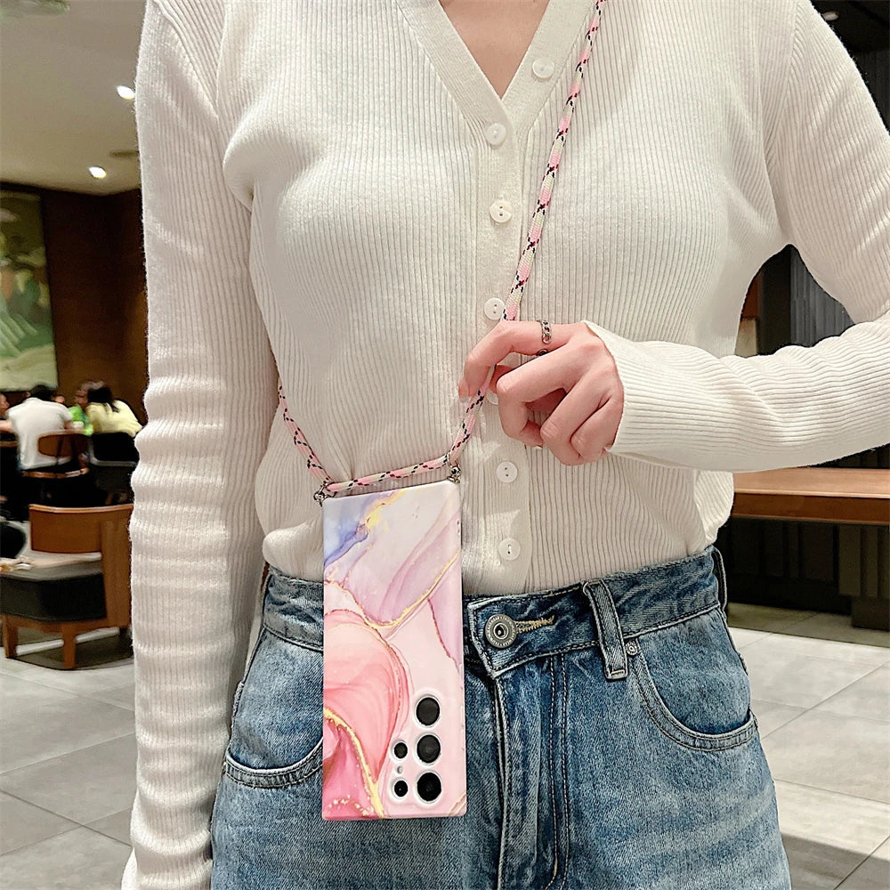 Smartphone case with a pink marble design and a chain strap worn as a crossbody accessory.