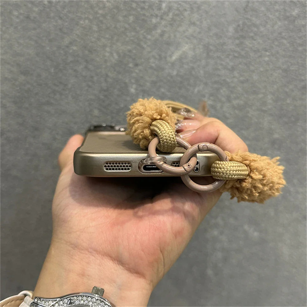 Smartphone in a protective case with a fuzzy charm.