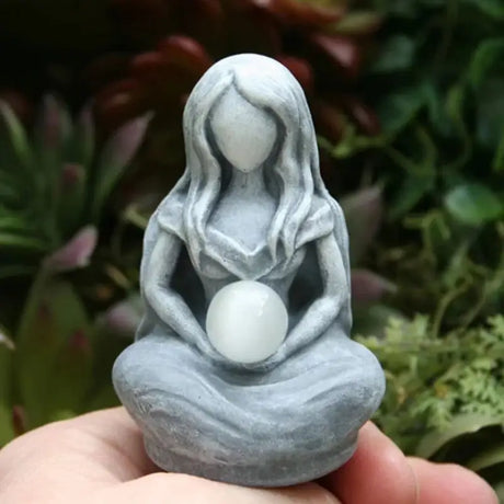 a small statue of a woman holding a white egg