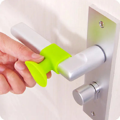 a hand holding a green handle on a white door