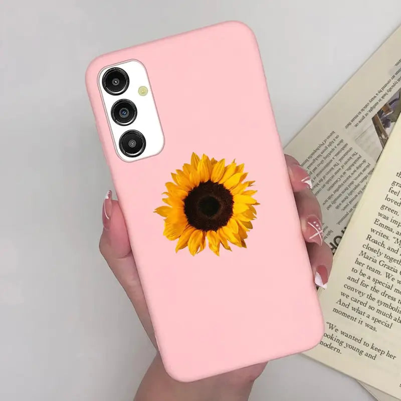 a woman holding a pink phone case with a sunflower on it