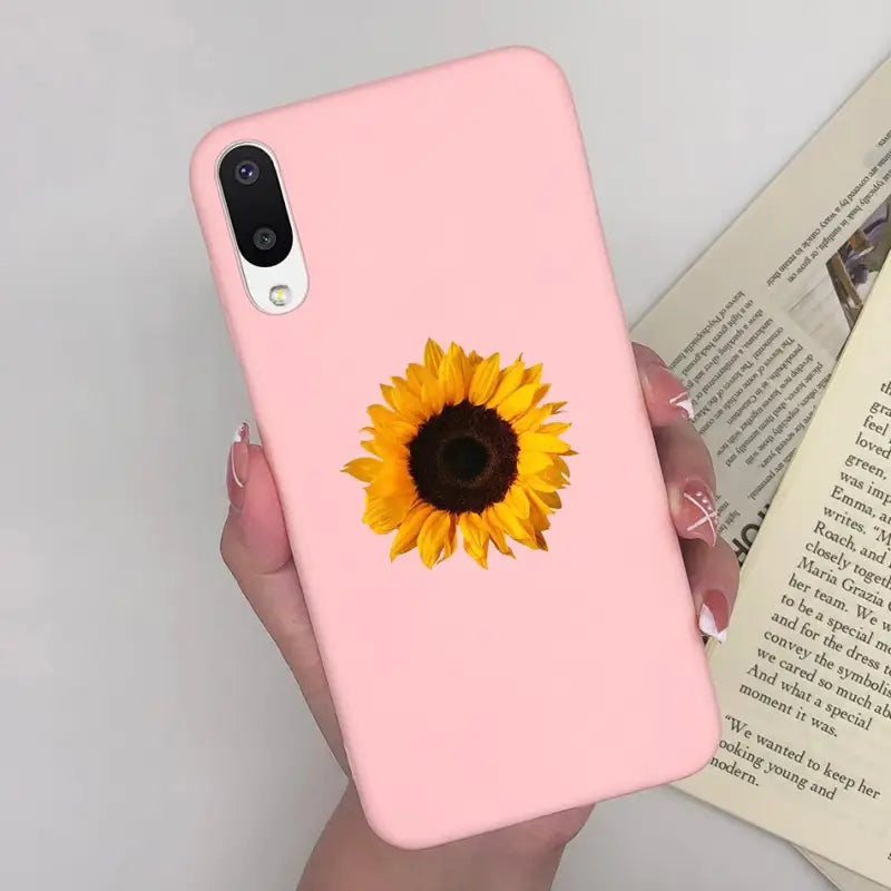 a woman holding a pink phone case with a sunflower on it