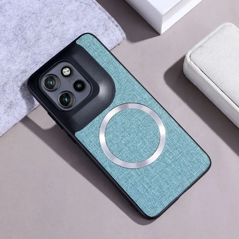 A teal fabric-textured phone case with a black camera module and a silver magnetic ring.