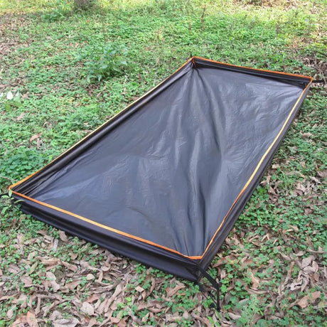 a tent with a black tar cover on the ground