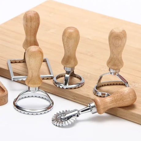 there are three wooden handles and a metal cutter on a cutting board