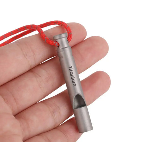 a hand holding a small metal device with a red cord