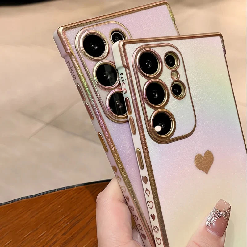 Two iridescent phone cases with gold accents and heart designs.