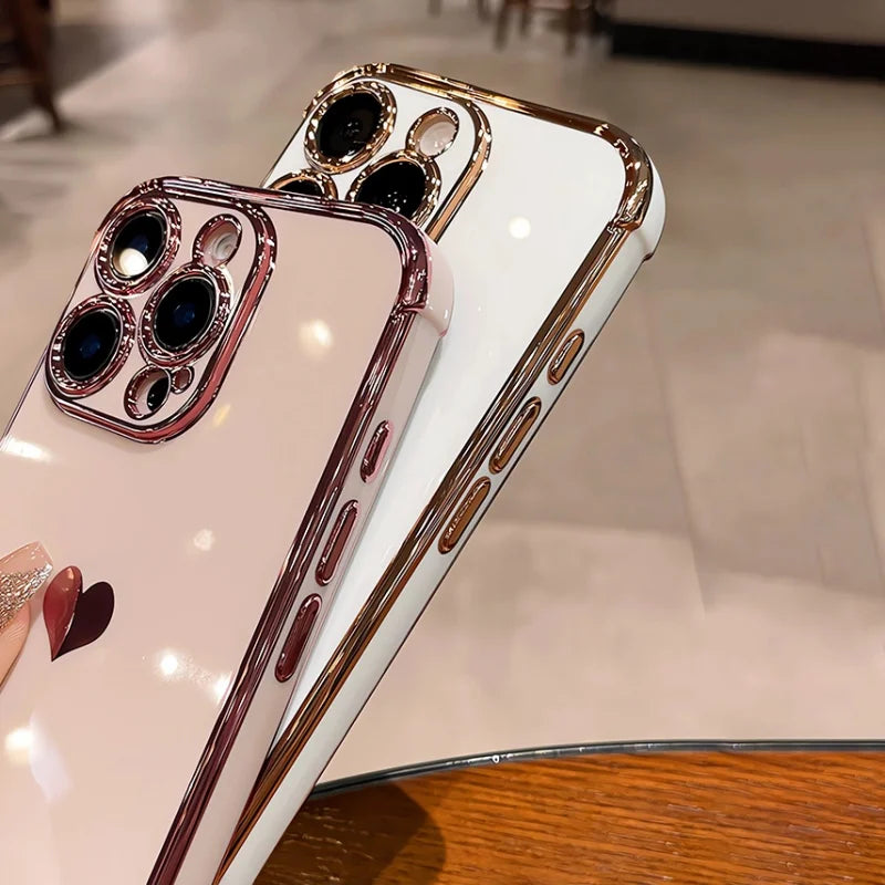 Two shiny phone cases, one pink and one white, both with gold-colored edges and camera protection.