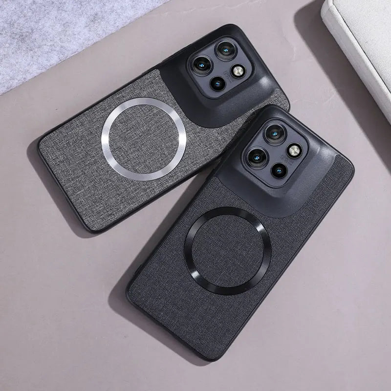 Two smartphone cases, one light gray and one dark gray, with integrated camera cutouts and circular magnetic charging rings.