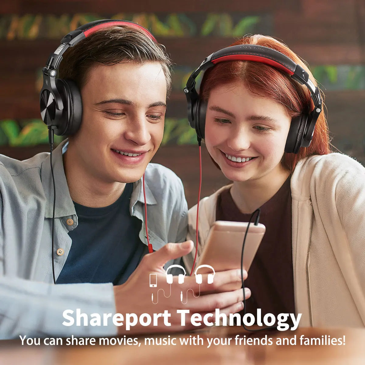 Two smiling young people wearing headphones and looking at a shared mobile device.